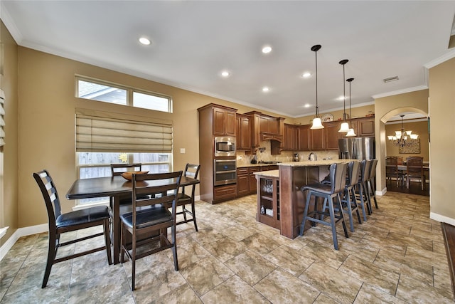 kitchen featuring appliances with stainless steel finishes, baseboards, tasteful backsplash, a kitchen breakfast bar, and a chandelier