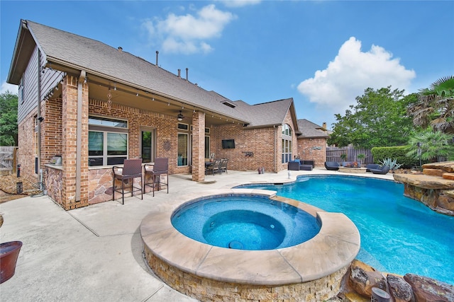 view of swimming pool featuring a patio, a fenced backyard, a pool with connected hot tub, and a ceiling fan