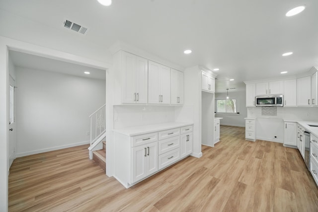 9711 Derrik Dr, Houston, TX 77080 - kitchen featuring white cabinets, light wood-type flooring, visible vents, and appliances with stainless steel finishes