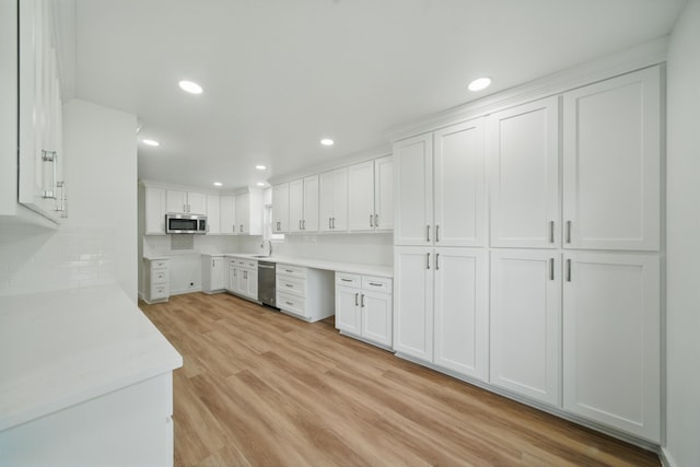 9711 Derrik Dr, Houston, TX 77080 - kitchen featuring white cabinets, stainless steel appliances, light countertops, light wood-style floors, and decorative backsplash