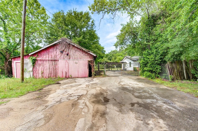 808 State Highway Loop 393, Goodrich, TX 77335 - view of outdoor structure with a carport, a gate, fence, an outdoor structure, and driveway
