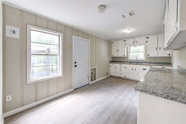 808 State Highway Loop 393, Goodrich, TX 77335 - kitchen featuring a sink, light wood-style flooring, white cabinets, light stone countertops, and baseboards