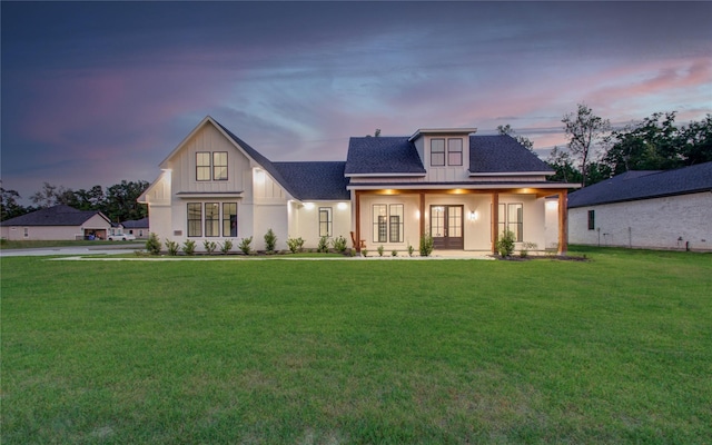 rear view of property with roof with shingles, a yard, board and batten siding, and french doors