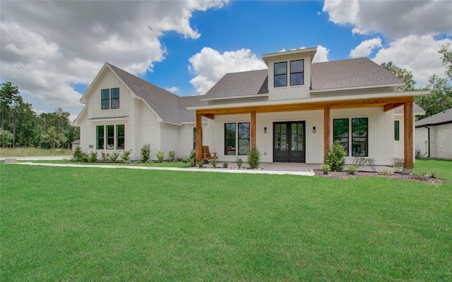 back of property with a lawn, board and batten siding, a shingled roof, and french doors