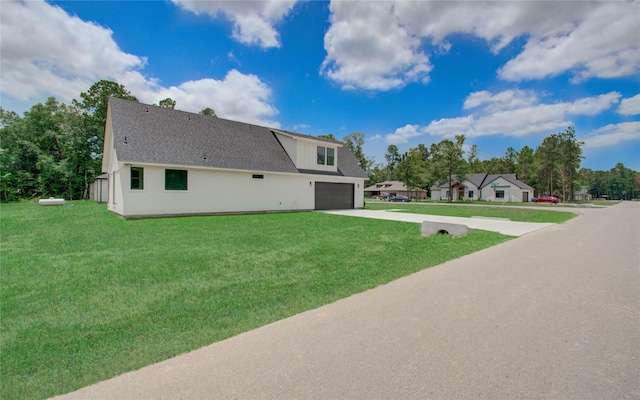 view of side of home featuring a shingled roof, a yard, stucco siding, driveway, and a garage