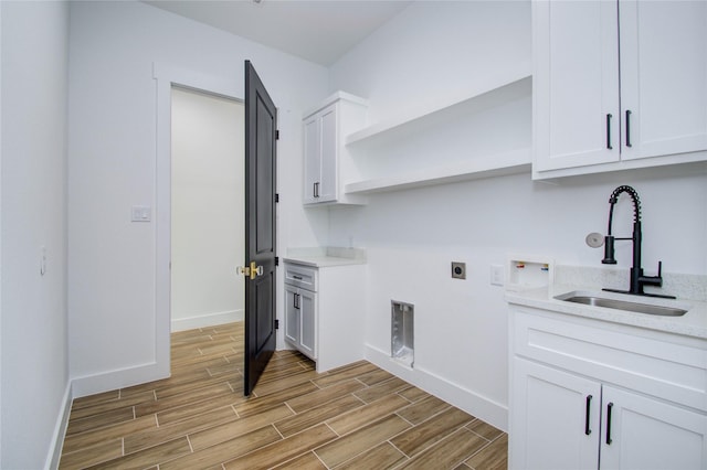 washroom with light wood finished floors, baseboards, electric dryer hookup, and a sink