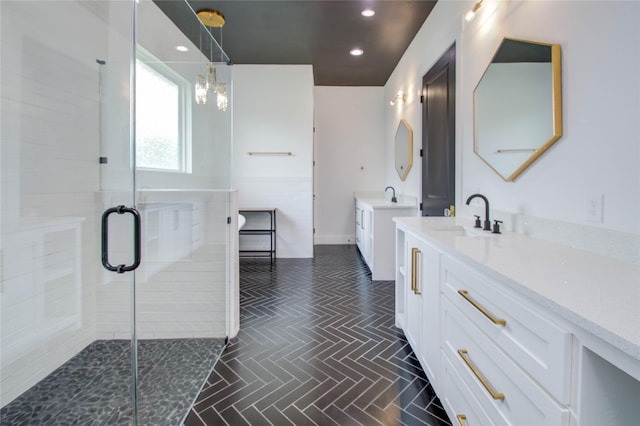 full bathroom with recessed lighting, two vanities, a shower stall, and a sink