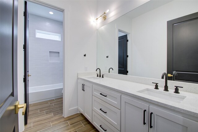bathroom featuring recessed lighting, double vanity, wood finished floors, and a sink