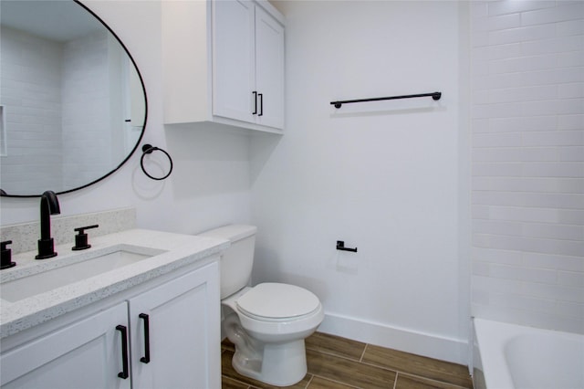 bathroom with toilet, vanity, wood finished floors, and baseboards