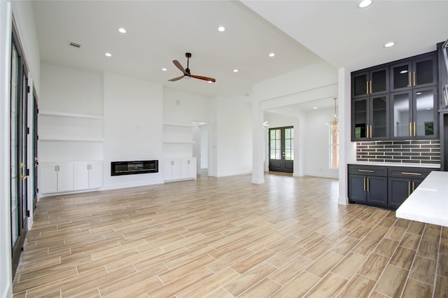 unfurnished living room with recessed lighting, visible vents, a ceiling fan, a glass covered fireplace, and light wood-style flooring