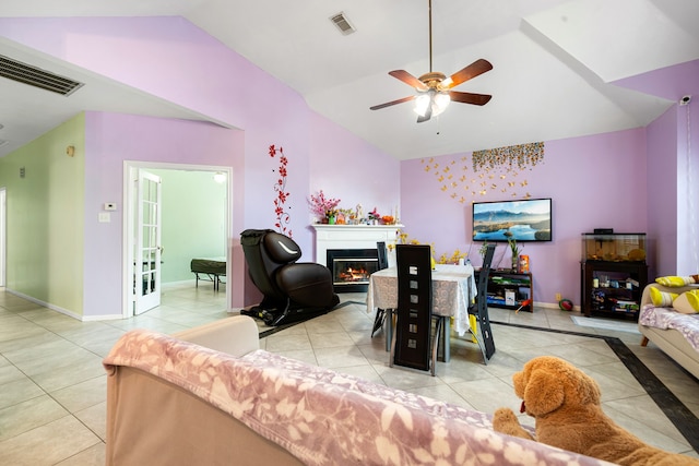living room with vaulted ceiling, visible vents, tile patterned flooring, and a lit fireplace