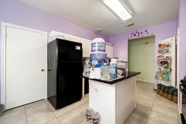 kitchen with white cabinets, light tile patterned floors, visible vents, and freestanding refrigerator