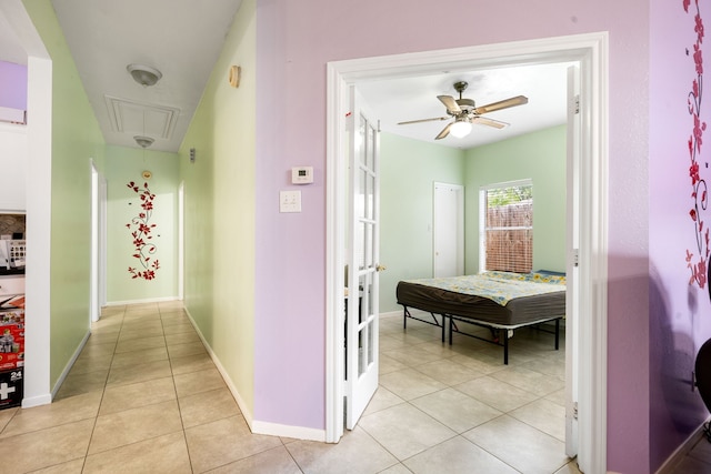 hall with attic access, baseboards, and light tile patterned floors