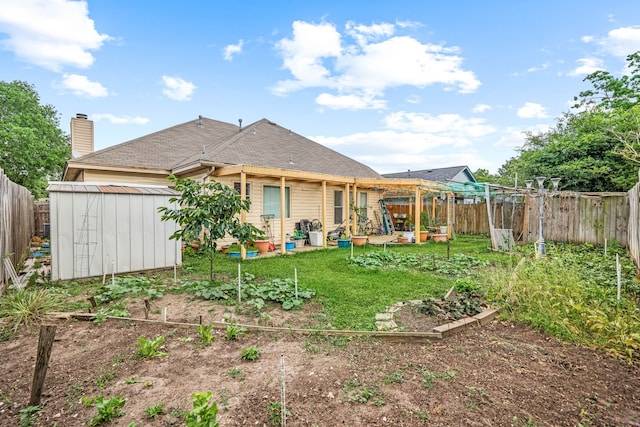 back of property featuring a yard, a garden, an outbuilding, and a fenced backyard