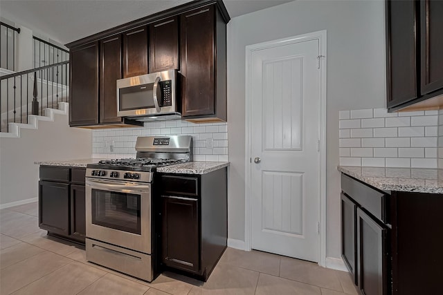 kitchen with decorative backsplash, appliances with stainless steel finishes, light stone counters, and light tile patterned floors