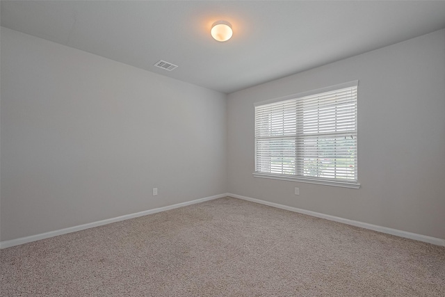 spare room with carpet floors, visible vents, and baseboards