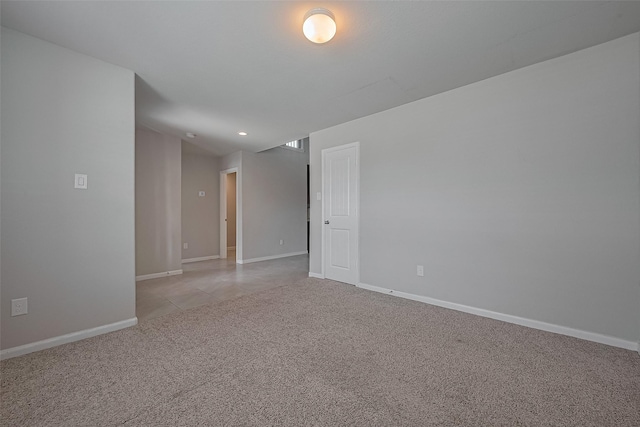 spare room with baseboards and light colored carpet