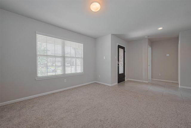 unfurnished room with light carpet, baseboards, recessed lighting, and light tile patterned flooring