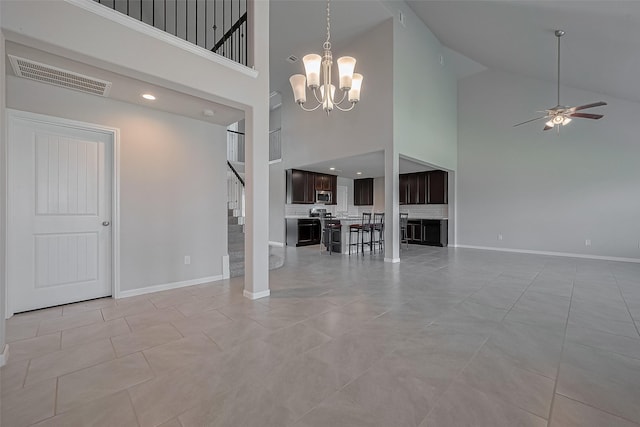 unfurnished living room with high vaulted ceiling, stairway, ceiling fan with notable chandelier, baseboards, and visible vents