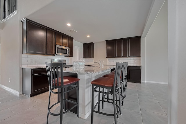 kitchen with backsplash, stainless steel appliances, visible vents, and light tile patterned floors
