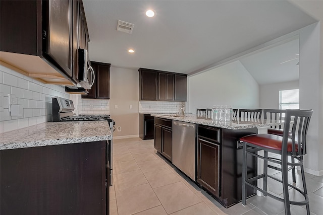 kitchen featuring visible vents, dark brown cabinetry, decorative backsplash, appliances with stainless steel finishes, and light tile patterned floors