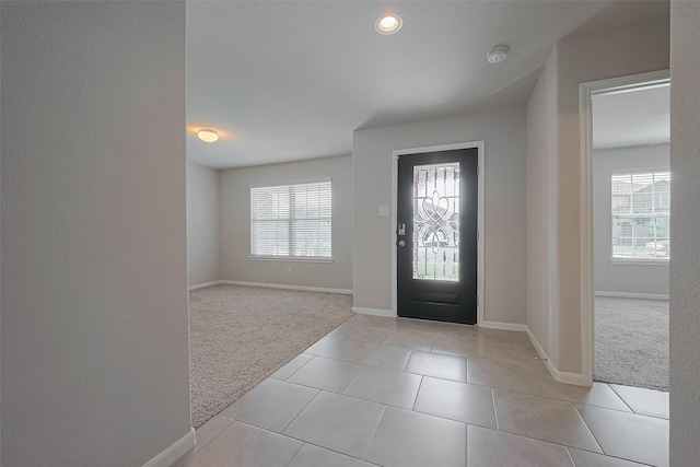 foyer featuring light tile patterned flooring, baseboards, and light carpet