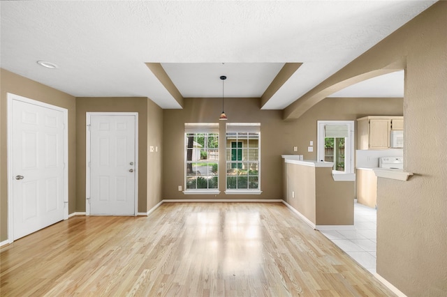 150 N Magnolia Pond Pl, The Woodlands, TX 77381 - unfurnished dining area featuring arched walkways, light wood-style floors, healthy amount of natural light, and baseboards