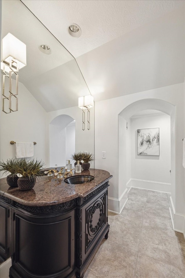 bathroom with baseboards, vaulted ceiling, and vanity