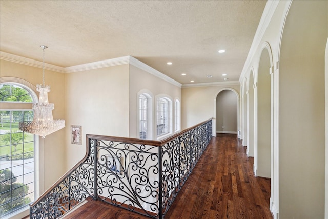 corridor with a chandelier, arched walkways, an upstairs landing, and wood finished floors