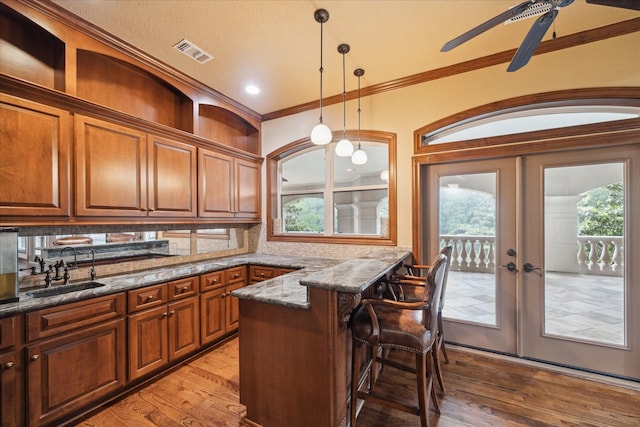 kitchen featuring a kitchen breakfast bar, a sink, visible vents, ornamental molding, and french doors