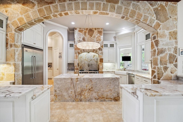 kitchen featuring ornamental molding, glass insert cabinets, light stone counters, arched walkways, and appliances with stainless steel finishes