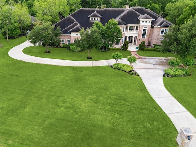 view of front of property featuring a front lawn, a balcony, and a chimney