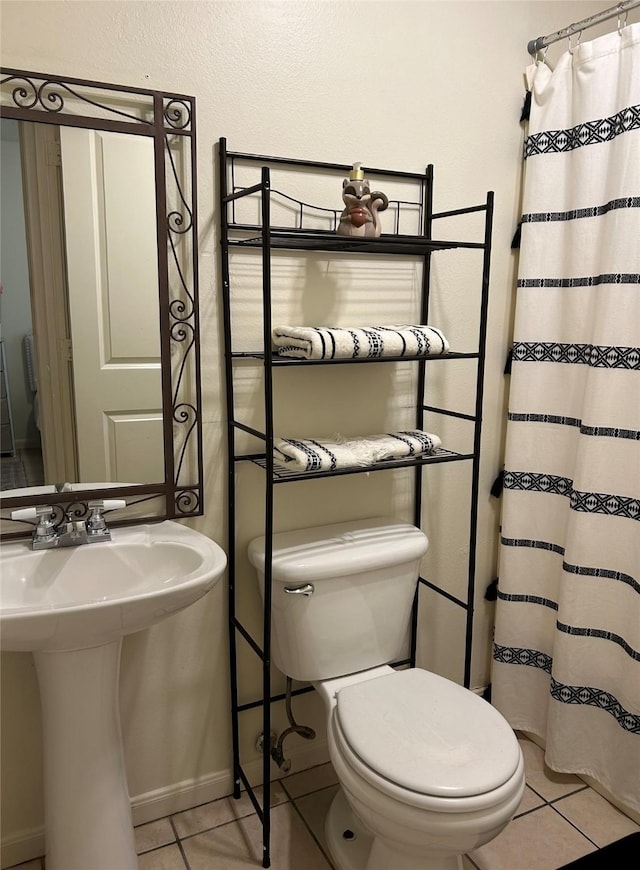 bathroom with a sink, toilet, baseboards, tile patterned flooring, and a shower with shower curtain