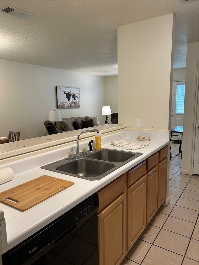 kitchen with a sink, light tile patterned flooring, light countertops, black dishwasher, and visible vents