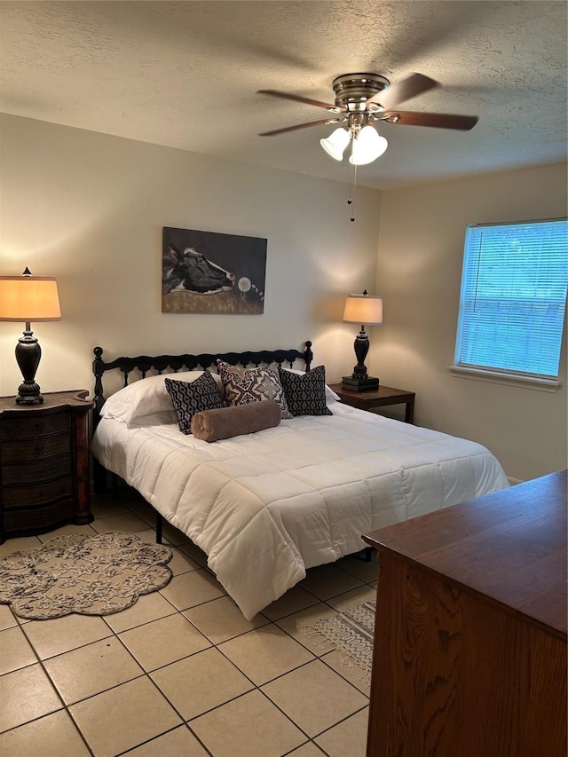 bedroom featuring a ceiling fan, a textured ceiling, and light tile patterned floors