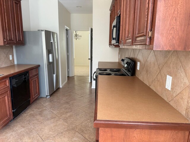 4923 Lake Gladewater Ct, Richmond, TX 77407 - kitchen with black appliances, decorative backsplash, light tile patterned flooring, and brown cabinets