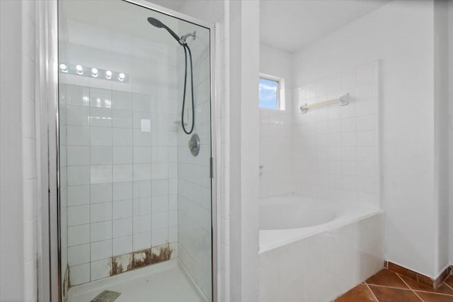 bathroom featuring baseboards, a bath, tile patterned floors, and a stall shower