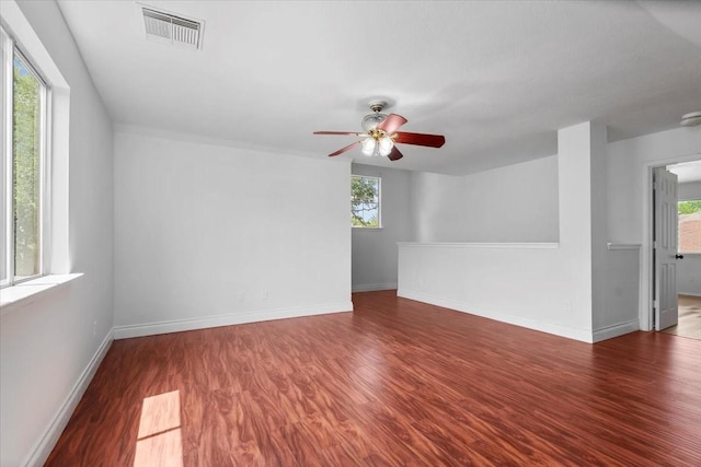 empty room featuring wood finished floors, visible vents, a ceiling fan, and a wealth of natural light