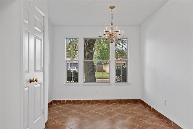 unfurnished dining area with a notable chandelier and dark tile patterned flooring