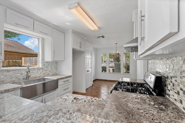 kitchen with a sink, stainless steel gas range, visible vents, a notable chandelier, and tile patterned flooring