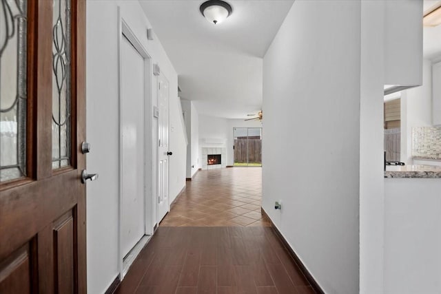 hallway featuring baseboards and dark wood-type flooring