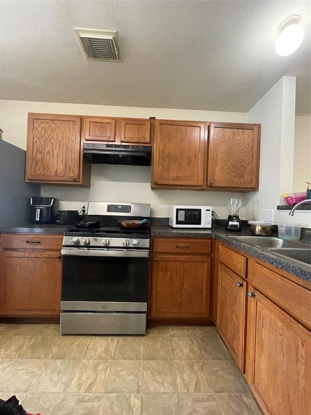 kitchen with visible vents, gas stove, a sink, white microwave, and under cabinet range hood