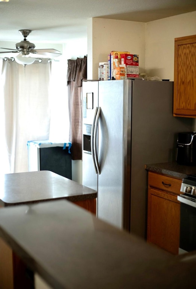 kitchen with a ceiling fan, brown cabinets, dark countertops, and stainless steel appliances