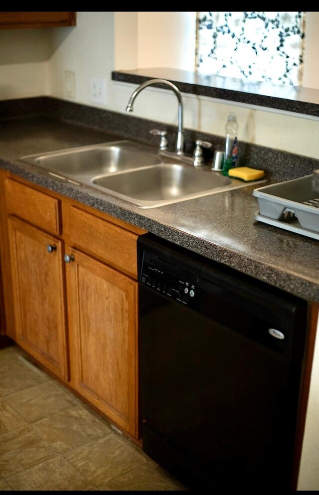 kitchen with a sink, black dishwasher, brown cabinets, and dark countertops