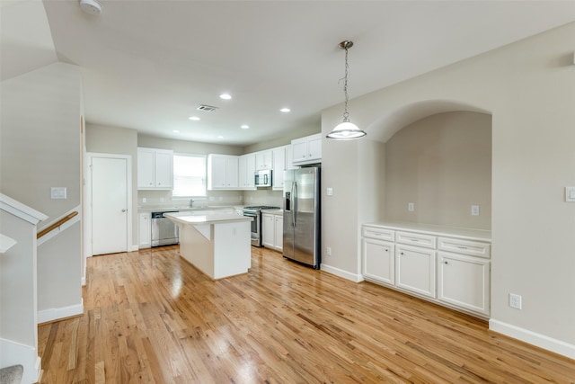 kitchen featuring light wood-style flooring, appliances with stainless steel finishes, a kitchen island, white cabinets, and visible vents