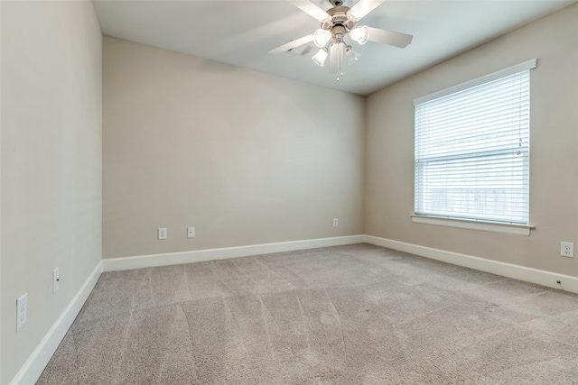 carpeted spare room with ceiling fan, a wealth of natural light, and baseboards