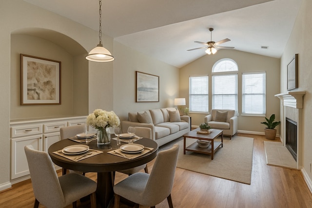 dining space featuring lofted ceiling, light wood-style floors, a ceiling fan, and visible vents