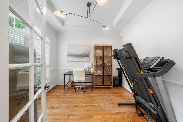 home office featuring crown molding, light wood-style floors, and a tray ceiling