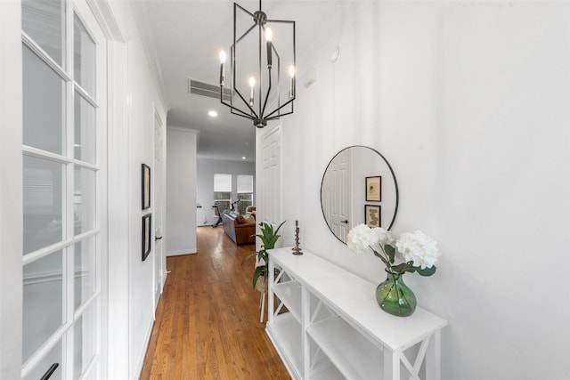 hall with visible vents, ornamental molding, wood finished floors, recessed lighting, and a notable chandelier