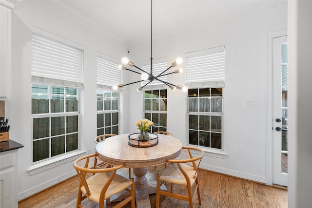 dining area with crown molding, light wood-style flooring, baseboards, and an inviting chandelier